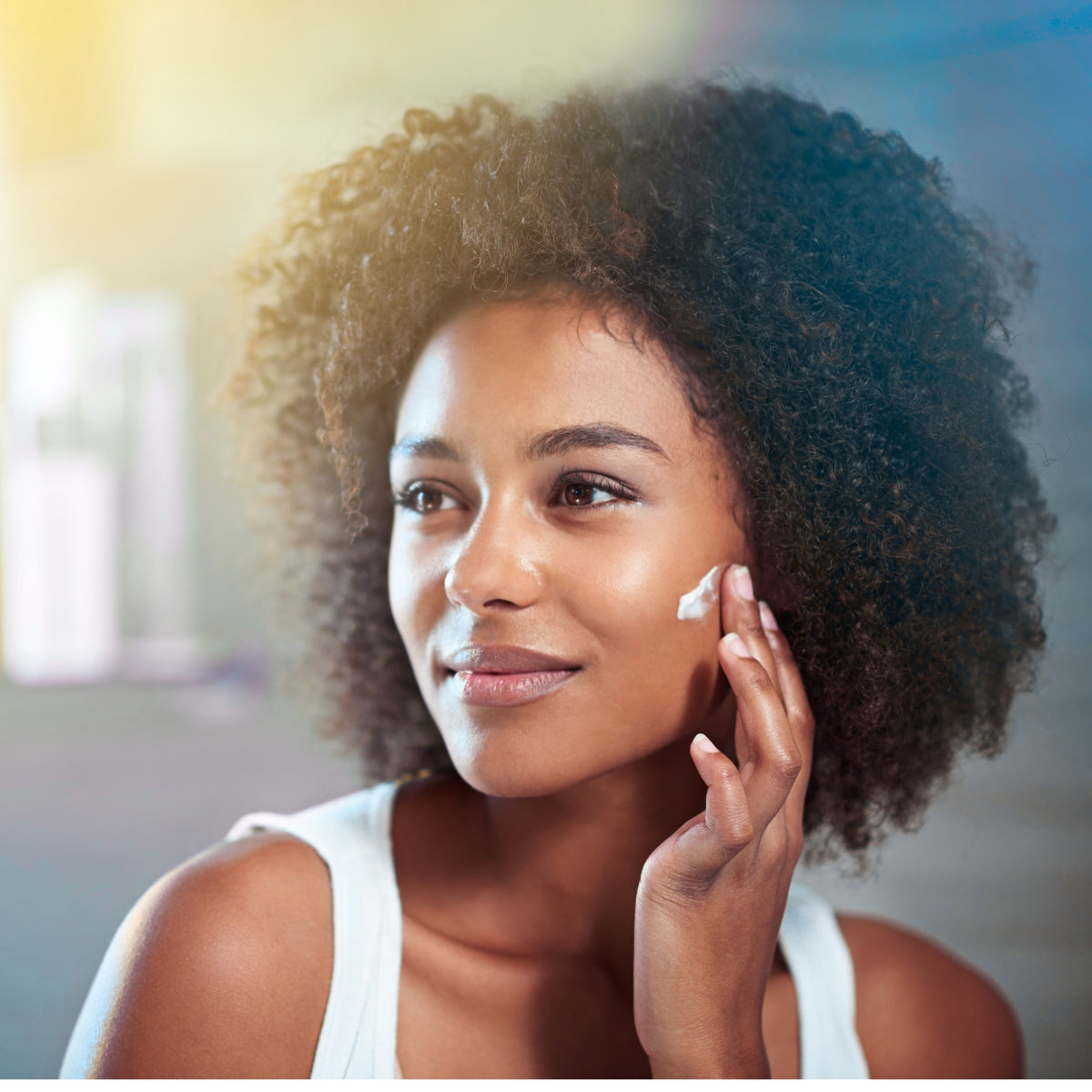 Woman applying skin cream, looking off into the distance | New Level Skincare